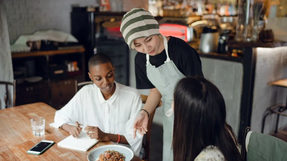 Restaurant server taking an order, a typical Alberta minimum wage job