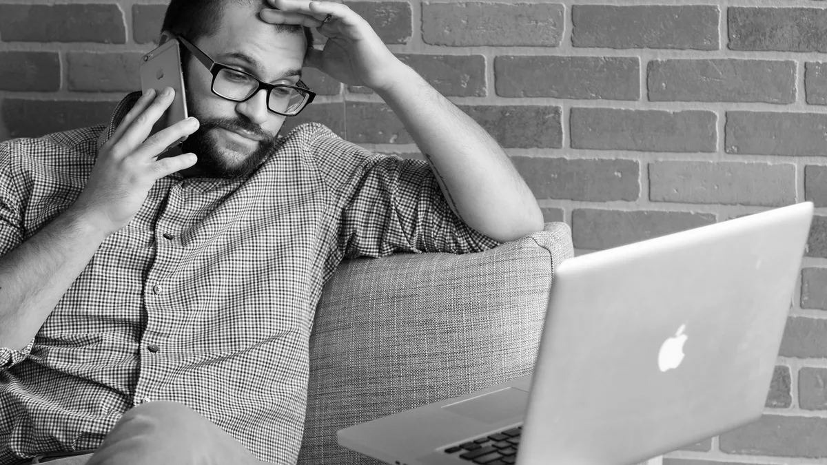Man calling Service Canada after a late EI payment with his laptop nearby