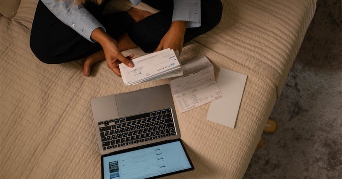 Person organizing bills and statements with a laptop to get out of debt in Canada