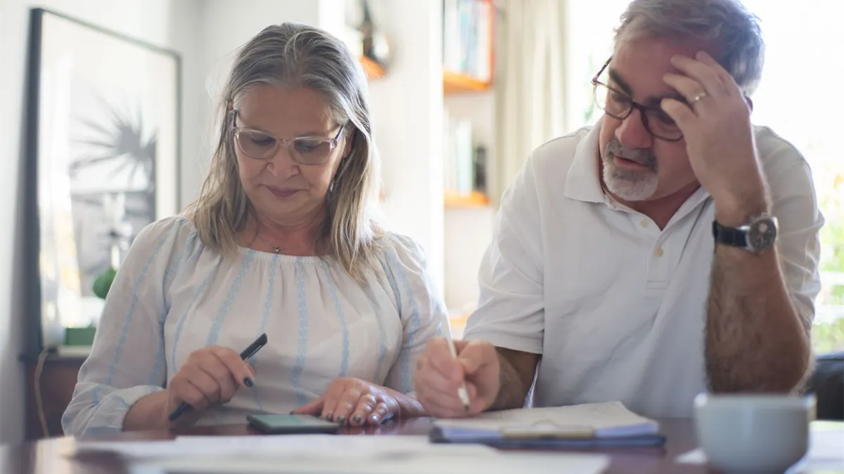 Retired couple budgeting around GIS payment dates with a calculator at home