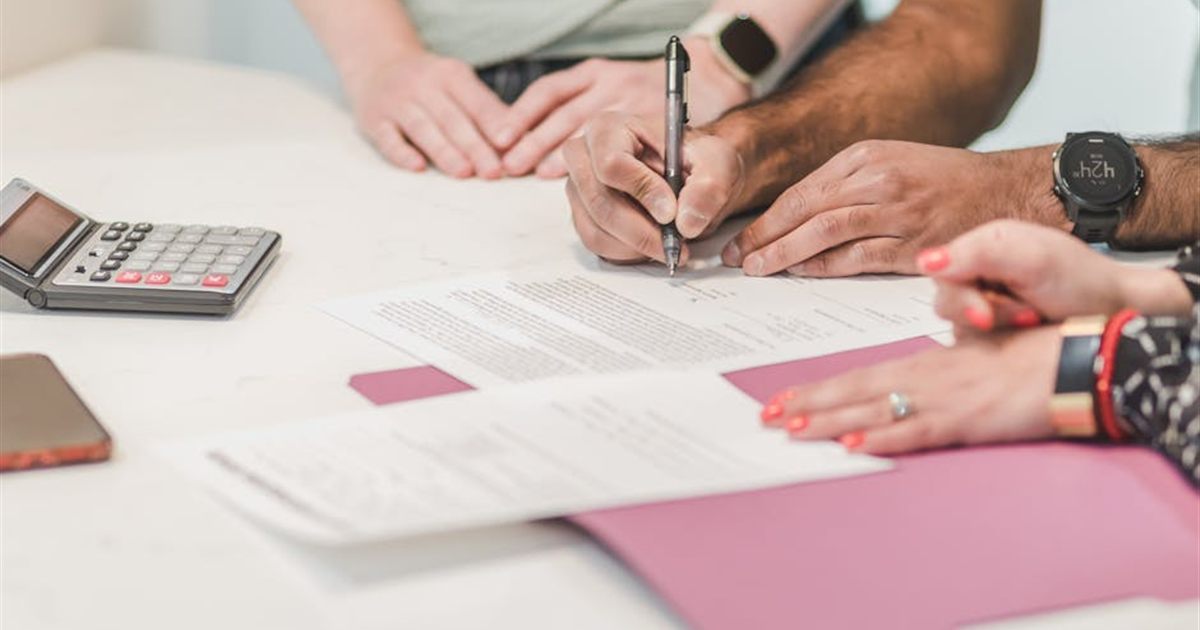 Couple signing a personal loan agreement with a calculator in Canada