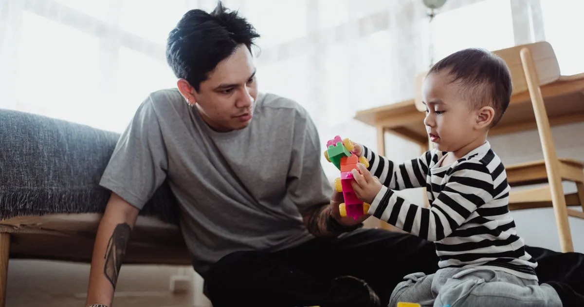Single father playing with his toddler son, eligible for the same single parent benefits in Canada