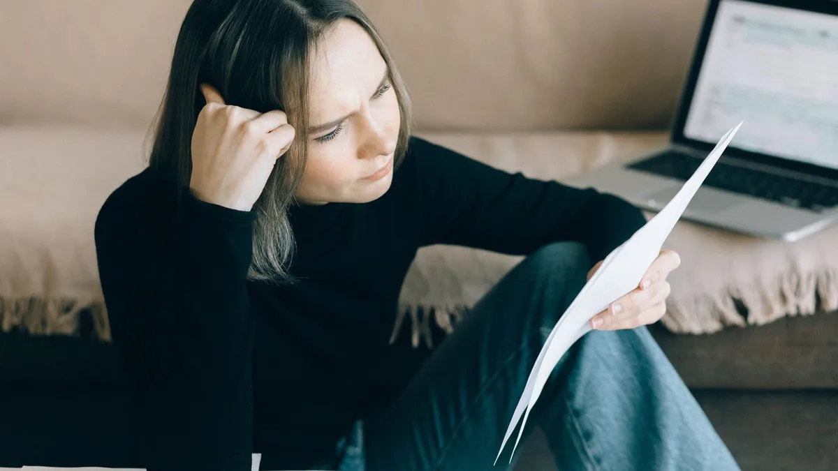 Woman reading her credit report at home and thinking through the consumer proposal disadvantages for her credit rating