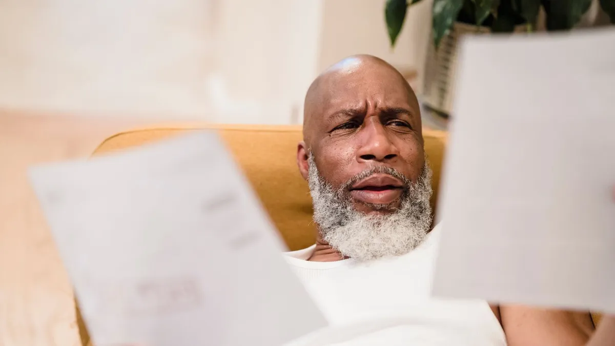 Man reading a letter from a creditor at home, one of the moments people compare a consumer proposal with bankruptcy