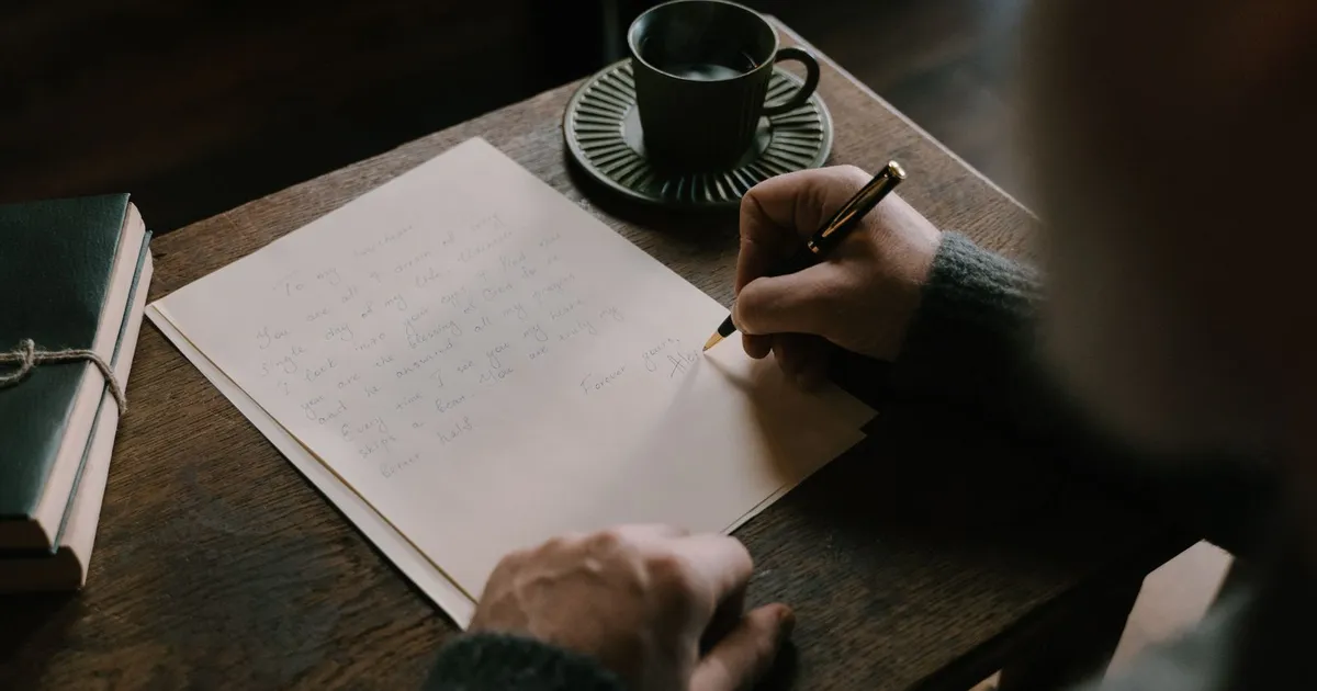 Hands filling in a document with a fountain pen at a wooden desk, the way you write a cheque by hand in Canada